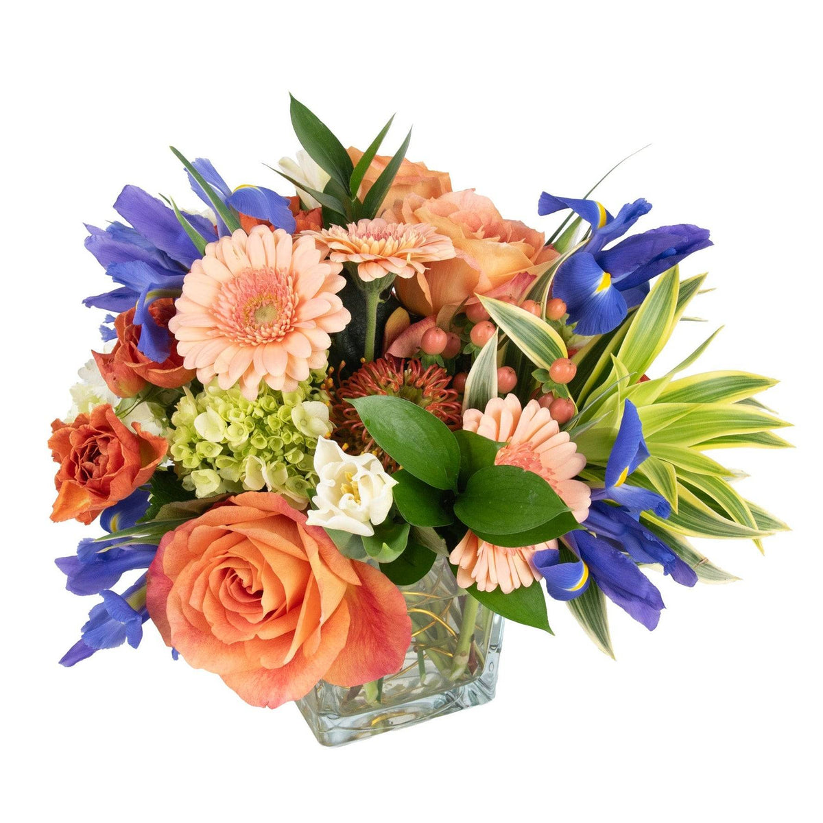 Colorful mixed fresh flowers arrangement in a clear glass cube vase with peach, pink, yellow, purple, and green blooms for celebration or gift
